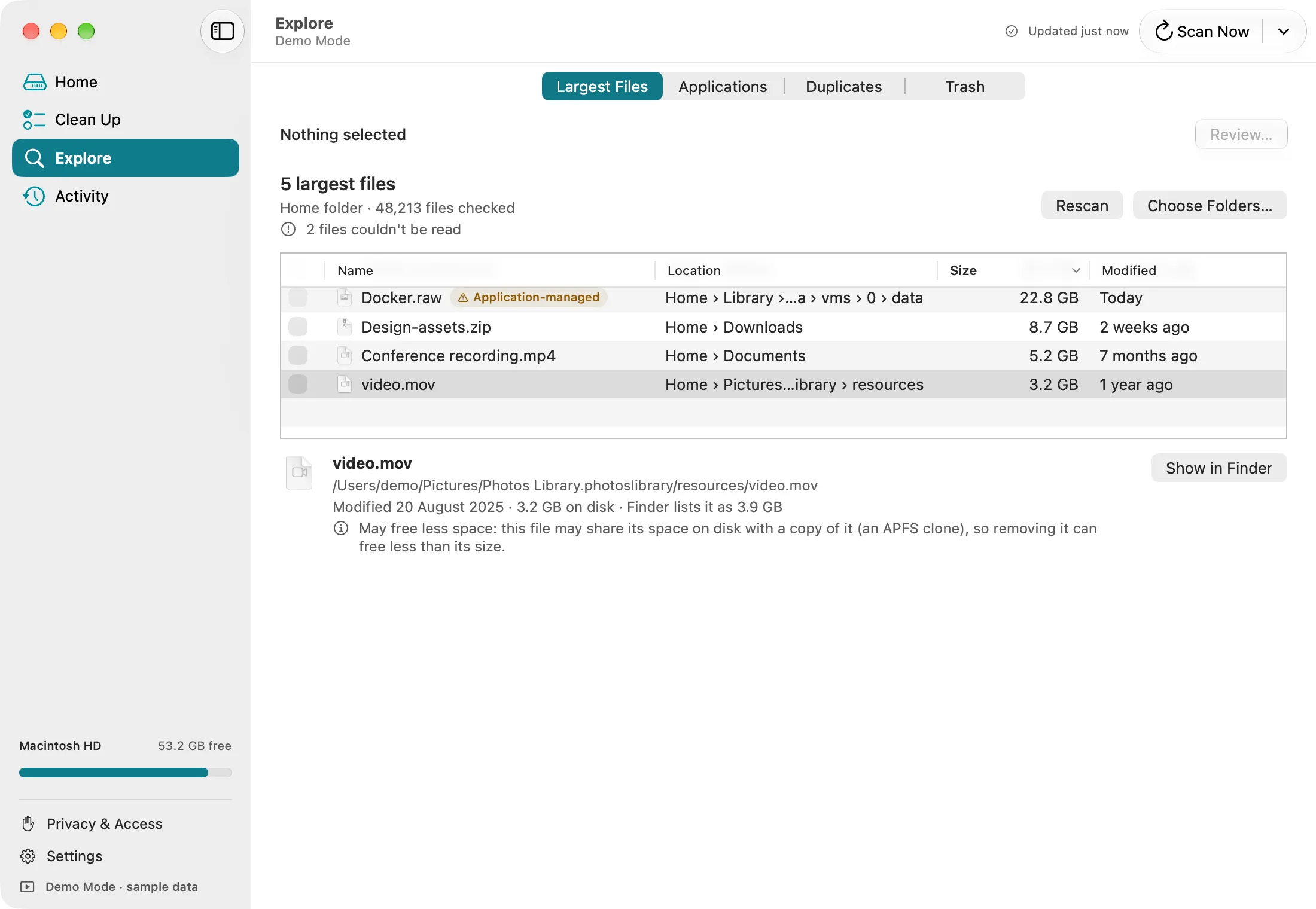 DiskFox's Largest Files list: Docker.raw at 22.8 GB, Design-assets.zip at 8.7 GB in Downloads, Conference recording.mp4 at 5.2 GB in Documents and video.mov at 3.2 GB inside the Photos library, with buttons to rescan or choose folders